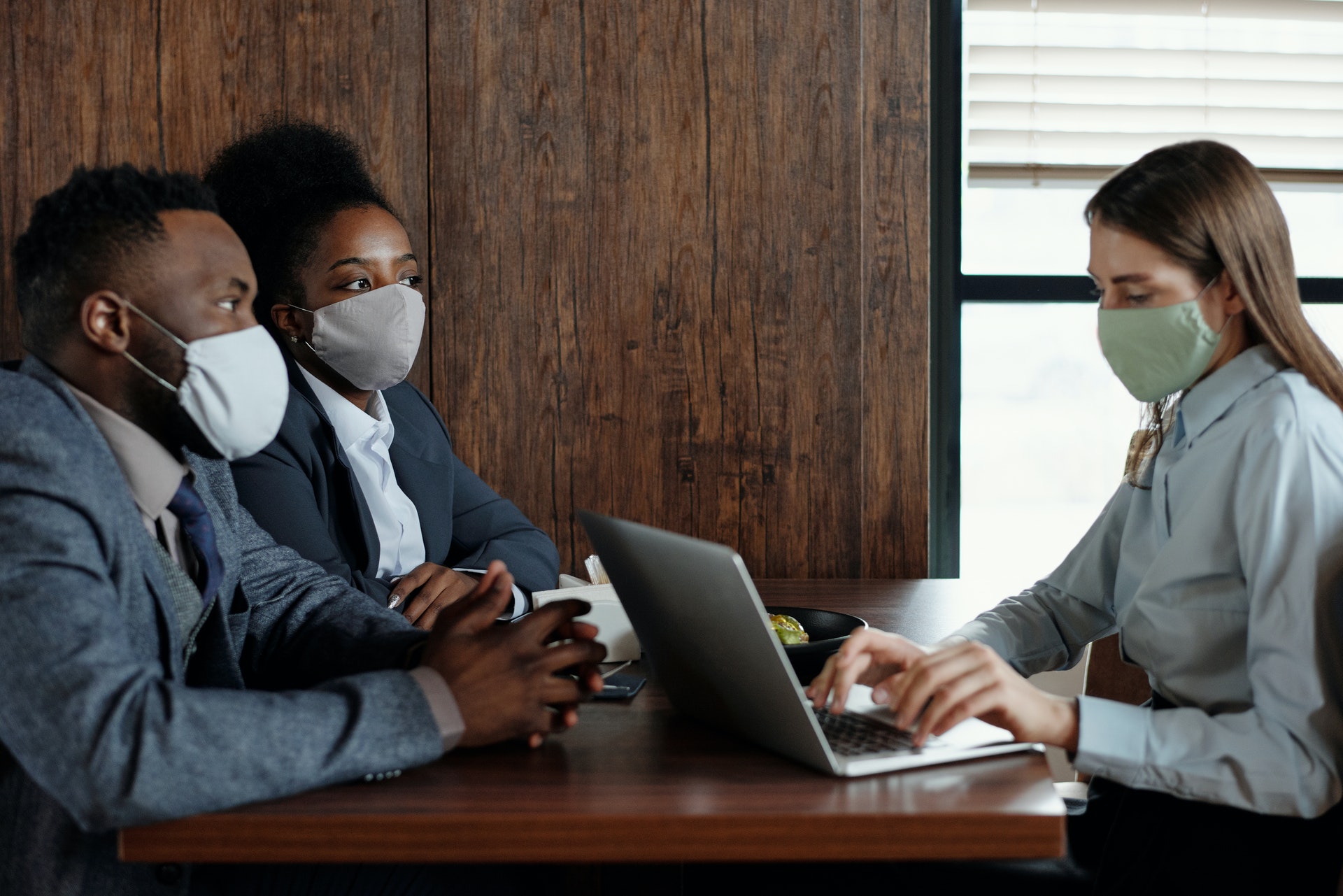 woman at computer with a couple in masks